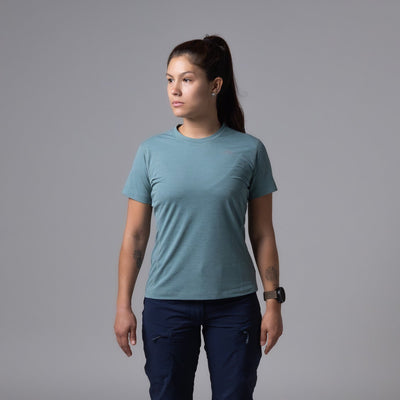 Person wearing a teal t-shirt and navy pants on a gray background